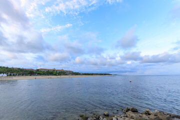 Beach with a cloudy sky and a few birds flying over the water