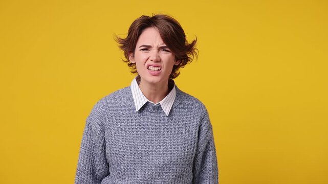 Indignant outraged sad young Caucasian woman she wear grey knitted sweater white shirt casual clothes swearing spread hands say no reject refuse isolated on plain yellow background. Lifestyle concept