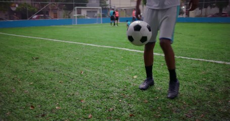African American Latin man practicing kick-ups on soccer field, balancing ball with precision and focus, concept of discipline, coordination, and dedication to athletic improvement