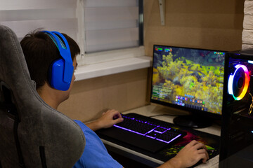 Person enjoys their free time by playing video games, wearing blue headphones for clear communication with friends while immersed in colorful, relaxing gaming environment