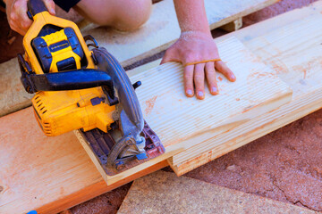 Worker utilizes power saw to cut plank of wood during DIY project