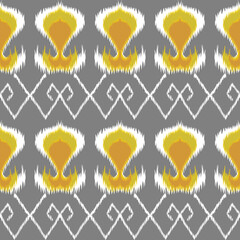 Geometric ikat pattern with diamond motifs in green and white on a warm yellow background, creating a bold and traditional textile design.