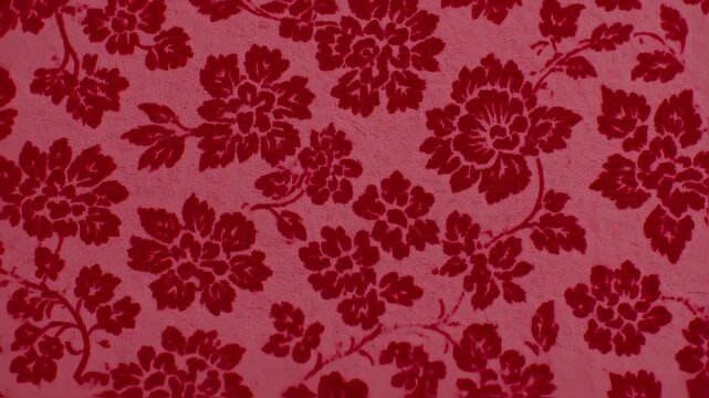 Deep red floral pattern on a light pink background.  A textured fabric with a repeating design of stylized flowers and leaves