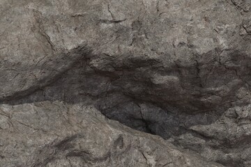 A textured close-up of a rugged, weathered gray rock face, showcasing natural cracks, crevices, and uneven surfaces under soft light and shadow
