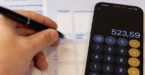 Gros plan sur une personne en train de remplir la déclaration des revenus des impôts pour...