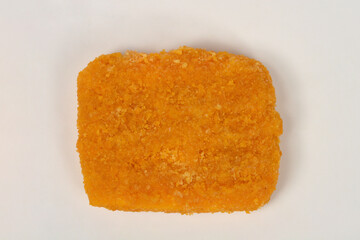 A top-down, studio image of a single piece of uncooked, breaded Trappist cheese