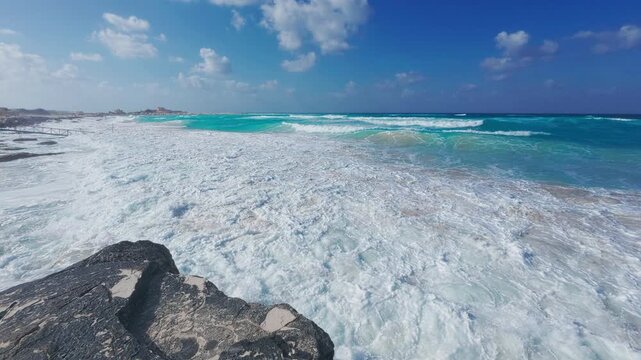 Handheld vertical footage of person climbing onto steep cliff above rushing sea and deep blue sky. Tropical atmosphere of North Coast of Egypt. Mediterranean sea coastline at Marsa Matrouh governorate