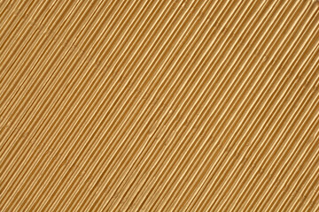 Fototapeta premium A full-frame macro shot captures the repeating texture of fine, diagonal ridges on a sheet of shiny metallic gold corrugated cardboard