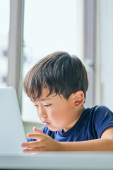 ノートパソコンでオンライン学習をする小学生の男の子