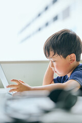 ノートパソコンでオンライン学習をする小学生の男の子