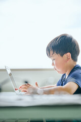 ノートパソコンでオンライン学習をする小学生の男の子
