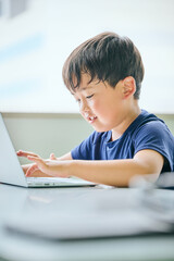 ノートパソコンでオンライン学習をする小学生の男の子