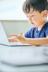 ノートパソコンでオンライン学習をする小学生の男の子