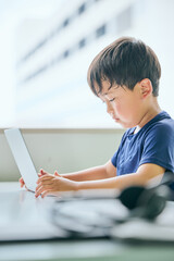 ノートパソコンでオンライン学習をする小学生の男の子