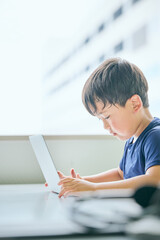 ノートパソコンでオンライン学習をする小学生の男の子