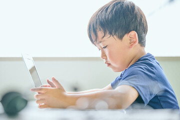 ノートパソコンでオンライン学習をする小学生の男の子