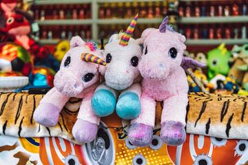 Three unicorn plush toy prizes at carnival game stall