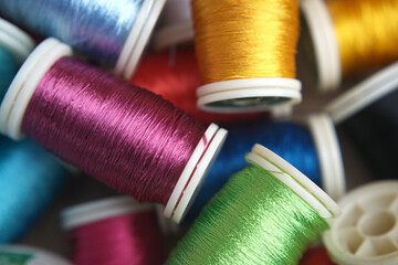 Close-up on a vibrant collection of spools, each meticulously wound with a rainbow of threads, creating a vivid tapestry of colors and textures.