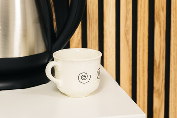 Small white cup of coffee on the edge of the table.