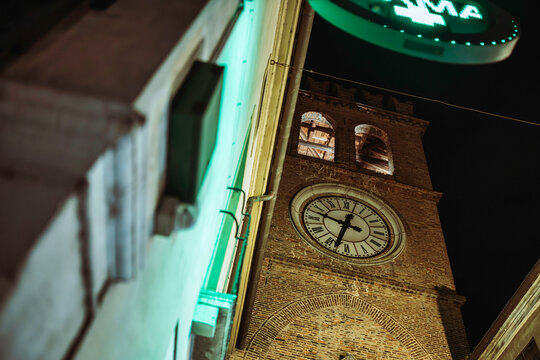 Lendinara clock tower at night with pharmacy sign