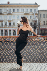 Elegant woman leaning on railing on city balcony