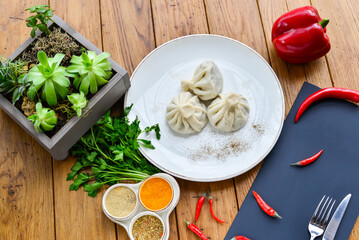 three khinkali in a white plate on a wooden table with decor