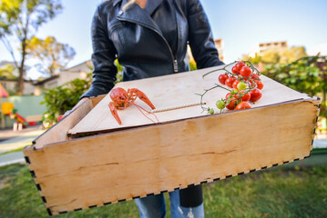 A box full of boiled crayfish in a girl's hands