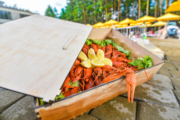 A box full of boiled crayfish against the background of a swimming pool