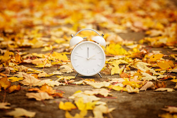 Daylight Savings Time Concept. A Clock And Leaves outside in autumn season