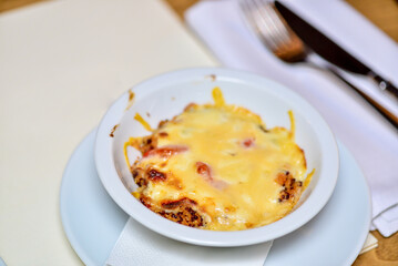 lozaniya with cheese in a white plate on the table