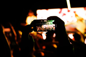 Smartphone recording live concert with bright stage lights