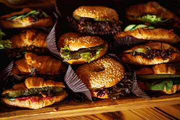 Variety of croissant and bagel sandwiches on wooden tray