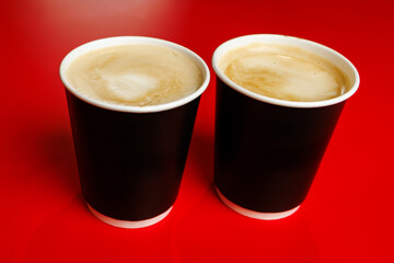 Two takeaway paper coffee cups on red background