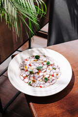 Seafood on a white plate with veggies in a cozy setting