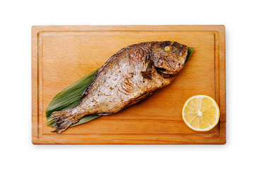 Grilled fish served on a wooden board with lemon slice for flavor