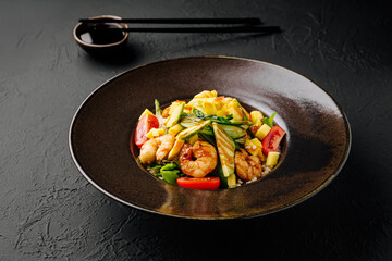 Shrimp stir-fry with vegetables served in a dark bowl on a textured surface