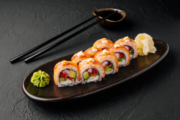 Delicious sushi rolls served on a dark plate with wasabi and ginger