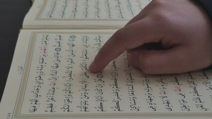 "istanbul, turkey 26.10.2025: In this close-up shot, a child is seen reading the Holy Quran. The child is reading the Quran by running his finger over the letters. 
