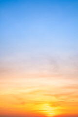 Sunset or sunrise sky with a vibrant gradient of orange, gold, and soft blue. Clear atmosphere with wispy clouds. Peaceful, natural light background. hope, freedom, new day Concepts, Vertical