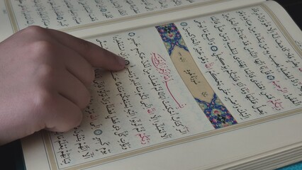 "istanbul, turkey 26.10.2025: In this close-up shot, a child is seen reading the Holy Quran. The child is reading the Quran by running his finger over the letters. 