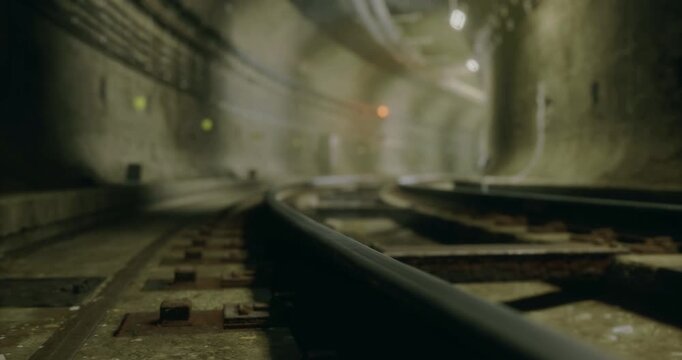 Rusty rails guide the eye into a shadowy underground tunnel, illuminated by soft lights. The atmosphere feels eerie as time seems frozen in this secluded space.
