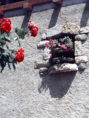 Window with flowers of an old house at Romeno, village in Trento province, Italy