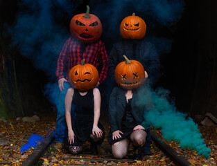 Four friends celebrate Halloween with pumpkin heads in a foggy forest setting during autumn