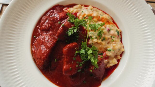 Traditional Hungarian goulash with tarhonya garnished with a sprig of parsley. High quality 4k footage
