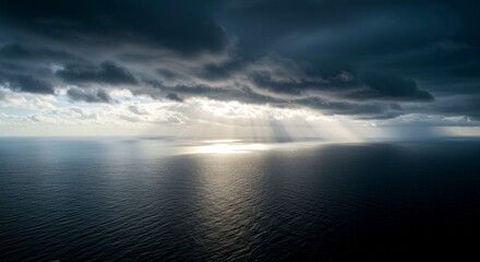 Obraz premium Dramatic seascape with dark clouds and sunlight reflecting on water 