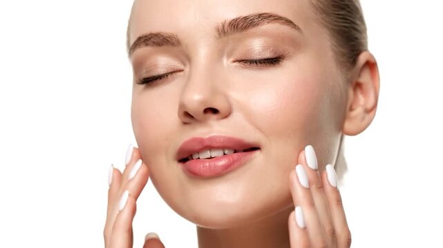 Close-up of a smiling woman gently touching her radiant face, eyes closed in bliss