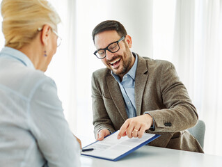 Portrait of a businessman and a businesswoman or real estate agent or doctor shaking hands and signing a deal contract with senior man or businessman in his office