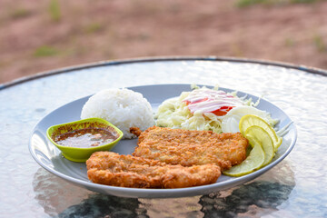 Two crispy fried fish fillets served with rice, salad, and spicy Thai dipping sauce.