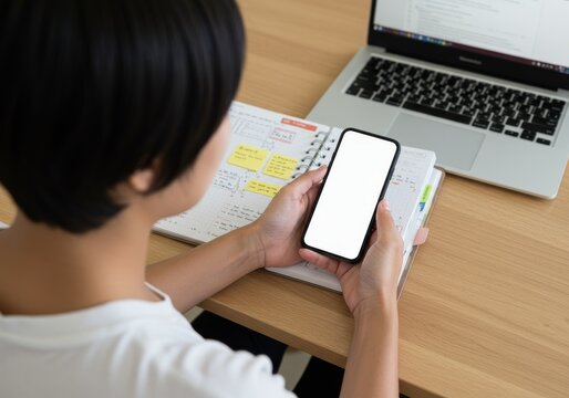 Person using smartphone with blank screen at desk.