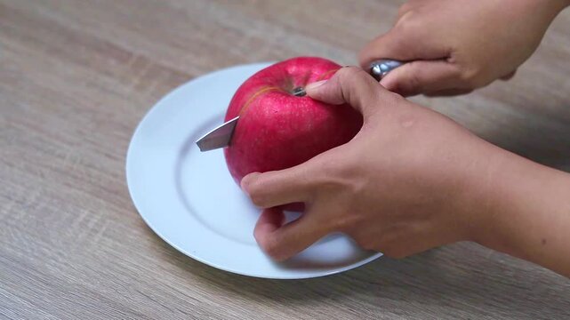 Hand holding a knife to halve an apple